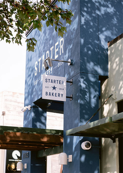 Starter Bakery sign on a blue building with tree shadows